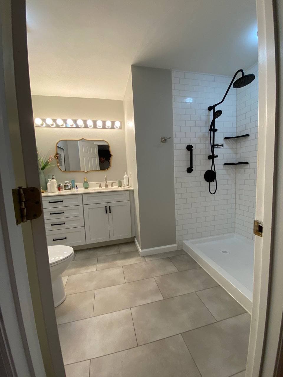 Updated shower walls and fixtures installed — white subway panels, black hardware, no glass door yet